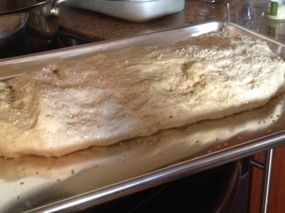 sweet bread dough shaped, risen, sprinkled with sesame seeds and ready for the oven in the afternoon sun